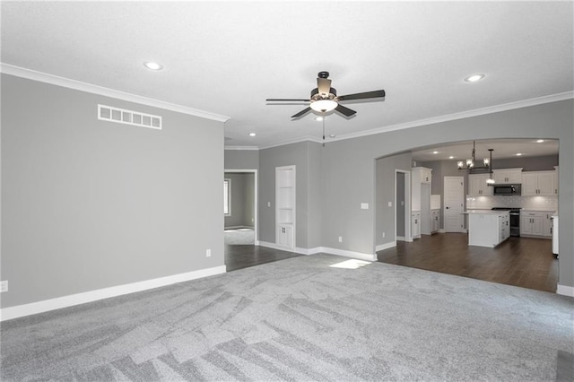 unfurnished living room with arched walkways, ceiling fan with notable chandelier, visible vents, baseboards, and dark colored carpet