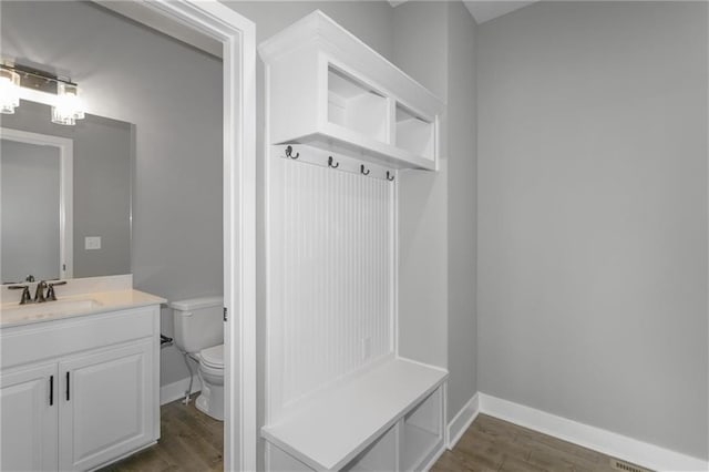 mudroom with a sink, baseboards, and dark wood-type flooring