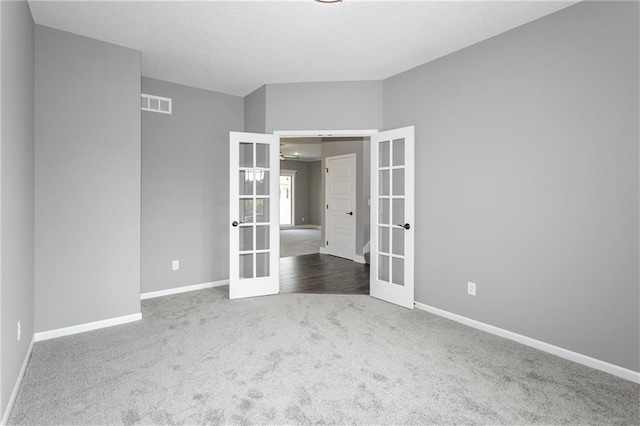 empty room with carpet floors, french doors, visible vents, and baseboards