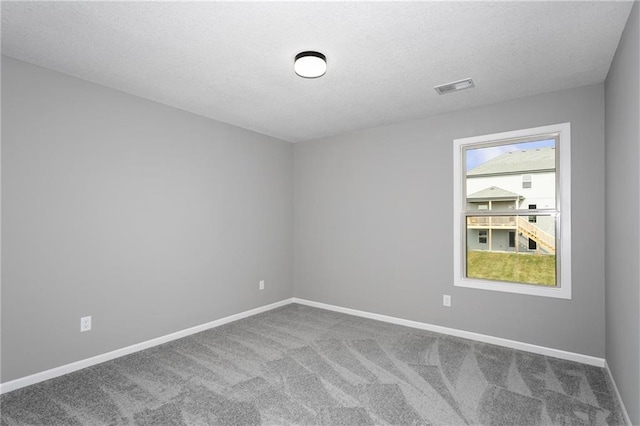 carpeted spare room featuring a textured ceiling, visible vents, and baseboards