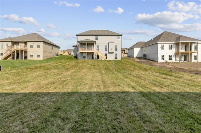 back of property featuring stairs, a lawn, and a residential view