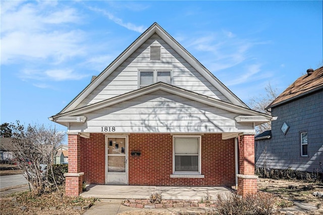 bungalow featuring covered porch and brick siding