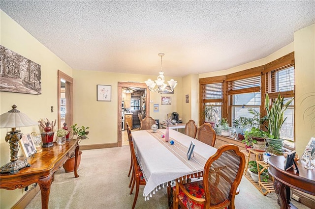dining room with light carpet, a textured ceiling, a chandelier, and baseboards