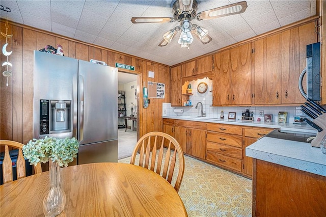 kitchen with a sink, stainless steel appliances, brown cabinetry, and light countertops