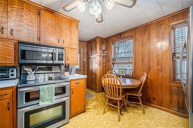 kitchen featuring brown cabinets, wooden walls, and stainless steel appliances