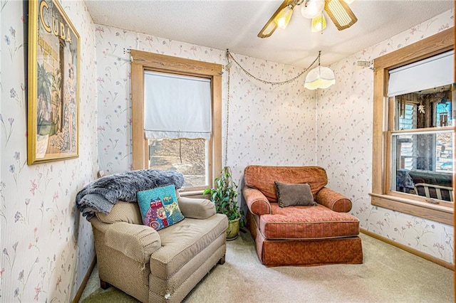 living area featuring a ceiling fan, carpet flooring, a textured ceiling, baseboards, and wallpapered walls