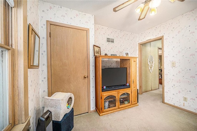 carpeted living room featuring wallpapered walls, visible vents, and a textured ceiling