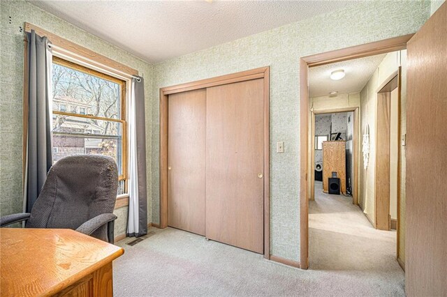 home office with wallpapered walls, a textured ceiling, and light colored carpet