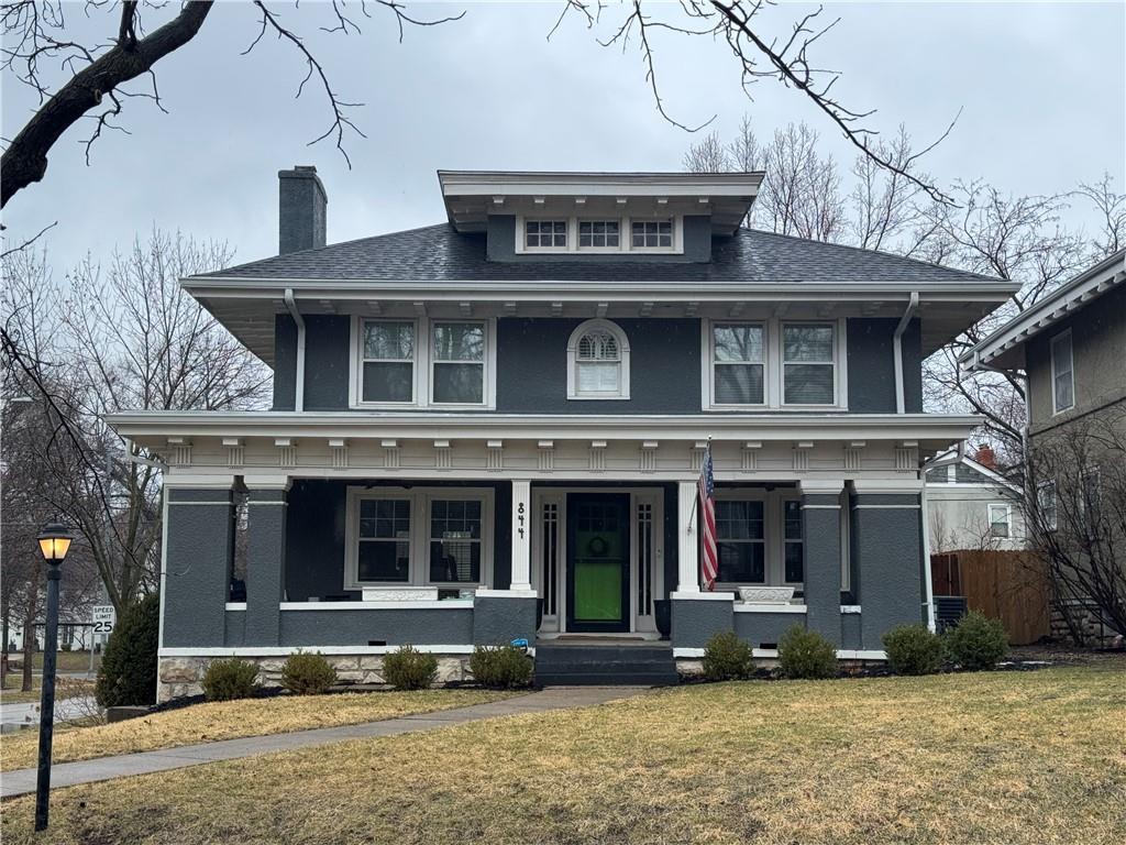 traditional style home featuring a shingled roof, a front lawn, fence, covered porch, and a chimney