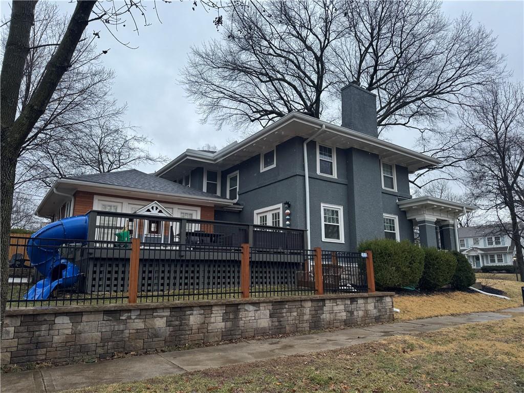 rear view of house featuring a wooden deck, stucco siding, and a chimney