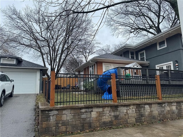 view of property exterior with fence, driveway, a wooden deck, a garage, and brick siding