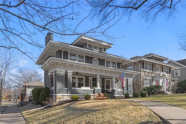 traditional style home with a porch, a chimney, a front yard, and a ceiling fan