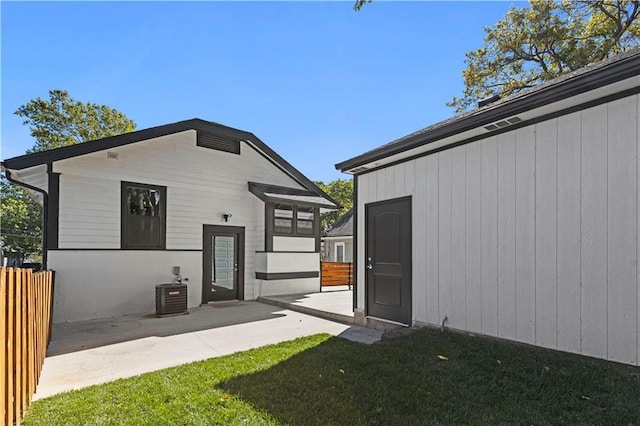 back of house featuring an outbuilding, central AC, fence, a lawn, and a patio area