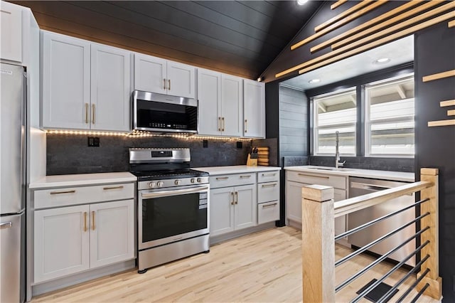 kitchen with lofted ceiling, stainless steel appliances, a sink, and light countertops