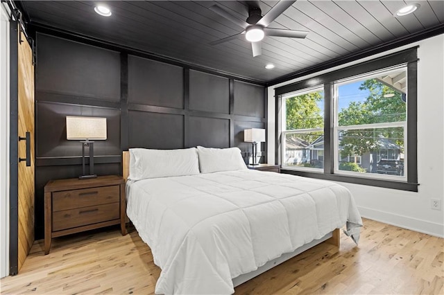 bedroom featuring recessed lighting, wooden ceiling, light wood-style flooring, and a decorative wall