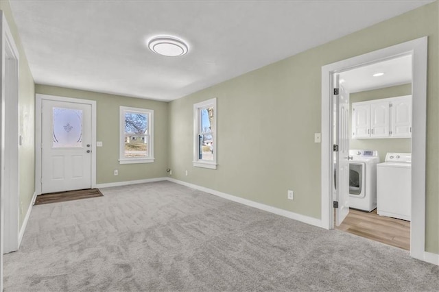 foyer with washer and clothes dryer, light colored carpet, and baseboards