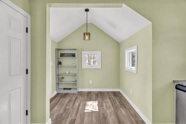 unfurnished dining area with vaulted ceiling, wood finished floors, and baseboards