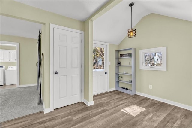 unfurnished dining area with baseboards, independent washer and dryer, wood finished floors, and vaulted ceiling