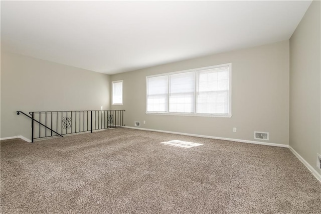 unfurnished room with carpet flooring, visible vents, and baseboards