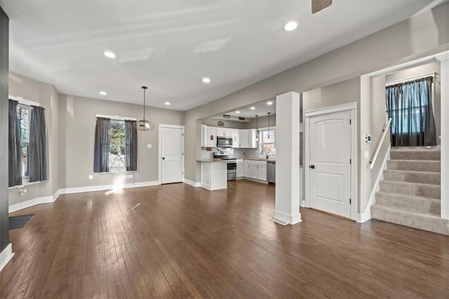 unfurnished living room featuring recessed lighting, baseboards, dark wood-style flooring, and a sink