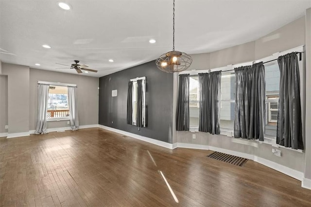 empty room with a ceiling fan, visible vents, wood finished floors, and baseboards