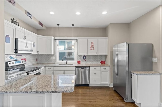 kitchen with a sink, stainless steel appliances, a peninsula, and white cabinetry