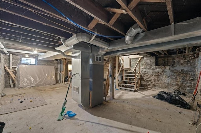 basement featuring stairway, heating unit, and visible vents