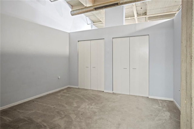 unfurnished bedroom with baseboards, multiple closets, and carpet