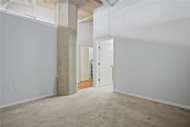 carpeted spare room with baseboards and a towering ceiling