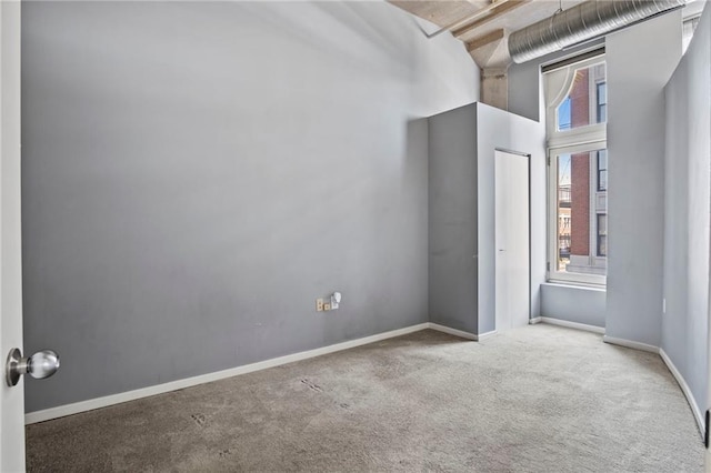 unfurnished bedroom featuring baseboards, carpet, and a towering ceiling