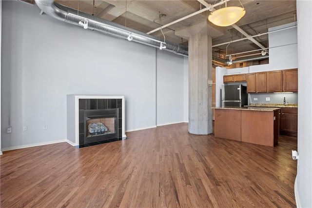 interior space with dark wood-style floors, a fireplace, freestanding refrigerator, a sink, and open floor plan