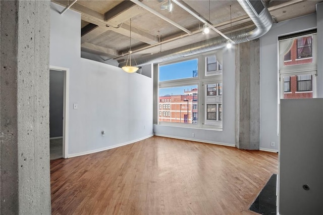 unfurnished dining area with a high ceiling, baseboards, and wood finished floors