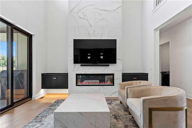 living room featuring baseboards, a premium fireplace, visible vents, and wood finished floors