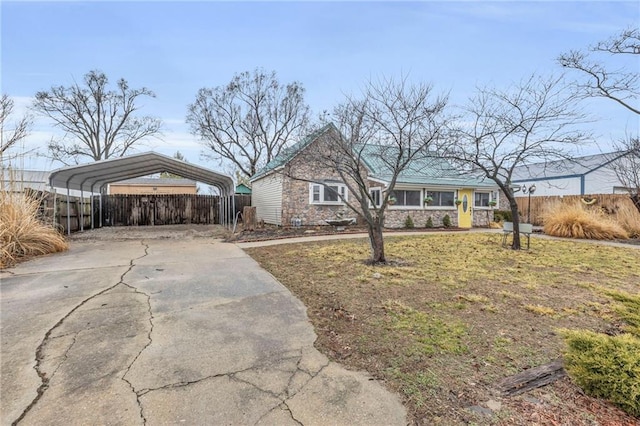 view of front of property featuring driveway, stone siding, fence, and a detached carport