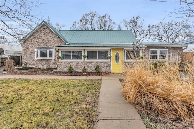 view of front of property with metal roof, stone siding, a front yard, and fence