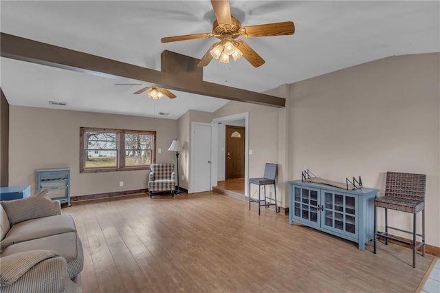 living room featuring a ceiling fan, vaulted ceiling with beams, baseboards, and wood finished floors