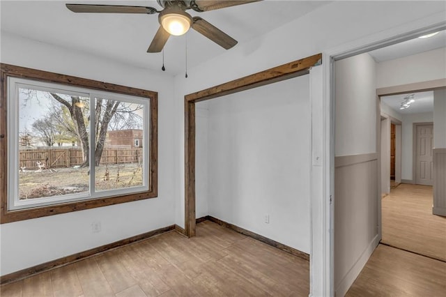 empty room featuring light wood-style flooring, baseboards, and ceiling fan