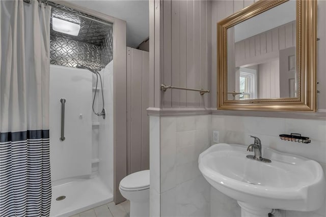 full bathroom featuring a sink, a shower stall, toilet, and tile walls