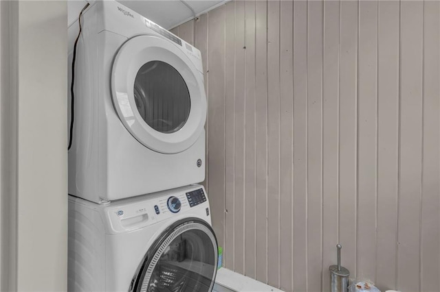 laundry area featuring stacked washer / dryer, laundry area, and wooden walls