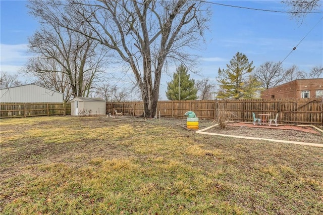 view of yard with a shed, a fenced backyard, and an outbuilding