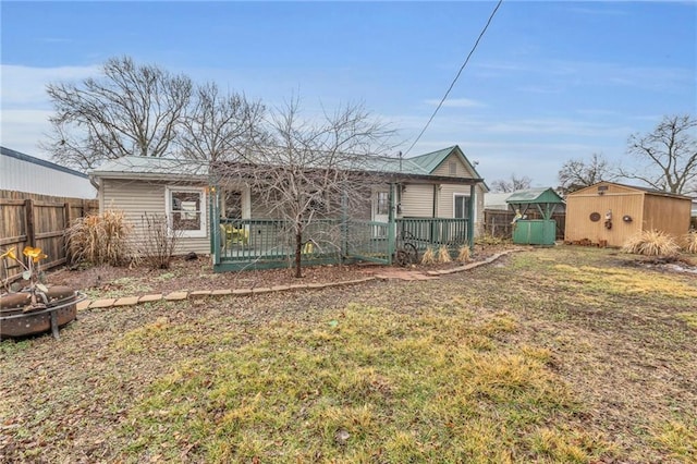 rear view of property with a yard, a shed, an outdoor structure, and fence