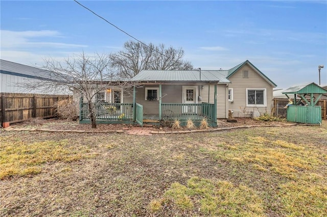 view of front of home with a porch, a fenced backyard, metal roof, and a front lawn