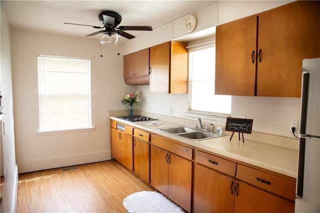 kitchen with a ceiling fan, a sink, light wood finished floors, light countertops, and freestanding refrigerator