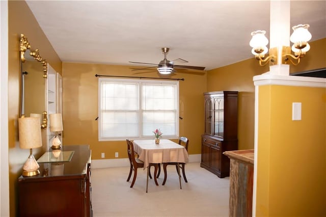 dining space featuring ceiling fan with notable chandelier, baseboards, and light colored carpet