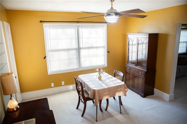 dining room with light carpet, baseboards, and ceiling fan
