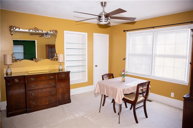 dining area featuring baseboards, light colored carpet, and ceiling fan