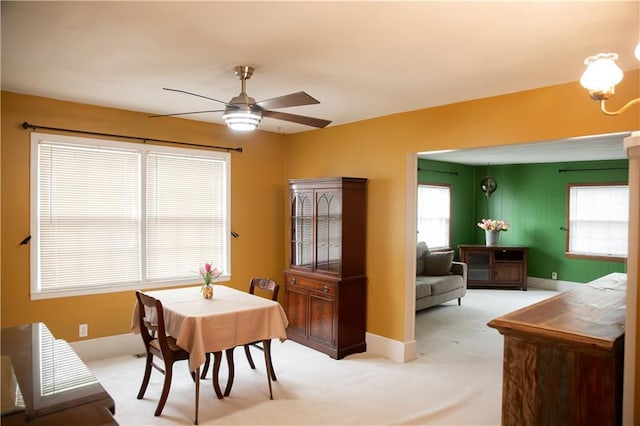 dining room featuring baseboards, light carpet, and ceiling fan with notable chandelier