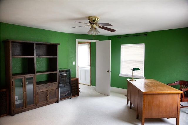 office featuring light colored carpet, ceiling fan, and baseboards