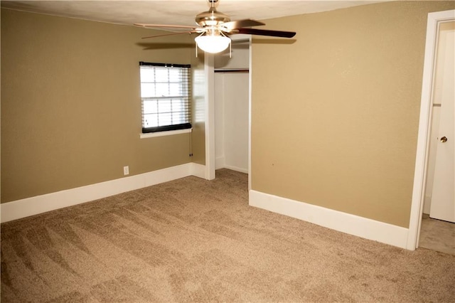 carpeted spare room with a ceiling fan and baseboards