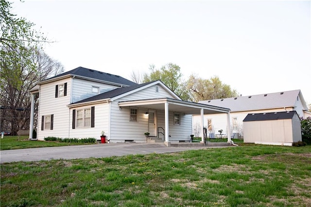 traditional home with a front lawn, an outdoor structure, an attached carport, and a shed